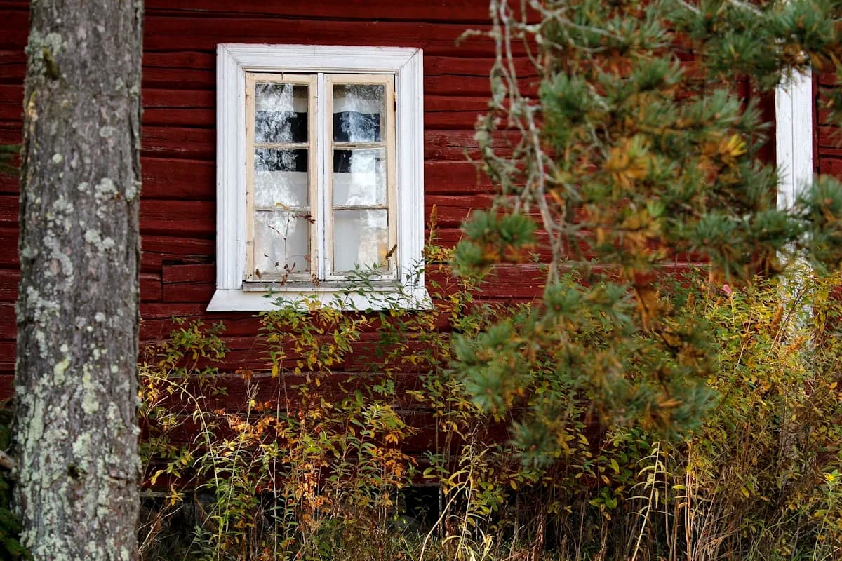 A white-framed multi-pane window in a red timber wall